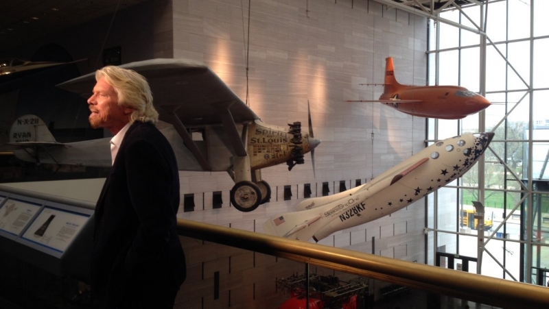  Ричард Брэнсон позирует на фоне аппаратов Spirit of St. Louis, SpaceShipOne и X-1 в галерее «Вехи полёта» 