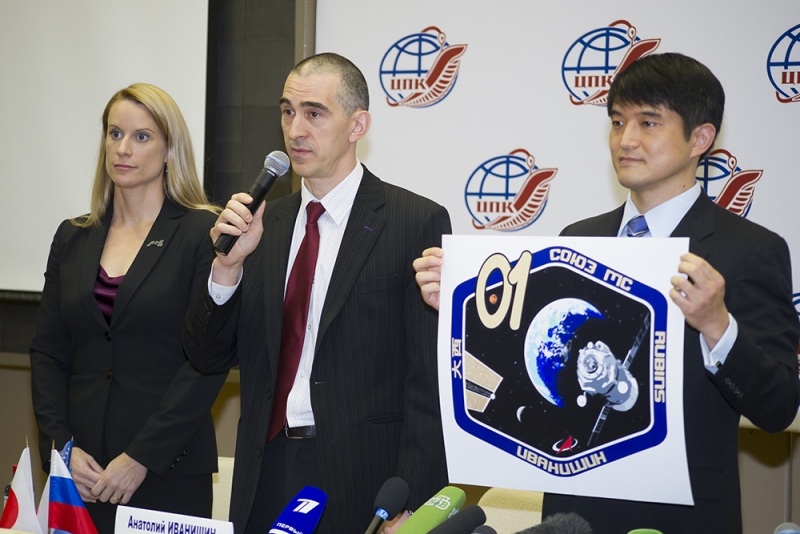  Экипаж корабля «Союз МС-01» Кэтлин Рубенс, Анатолий Иванишин и Такуя Ониси представляют эмблему полёта 