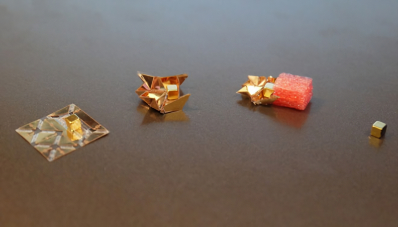  Оригами-робот в разложенном состоянии (слева) с магнитом сверху; в собранном виде; толкающий груз; постоянный магнит отдельно (источник: MIT) 