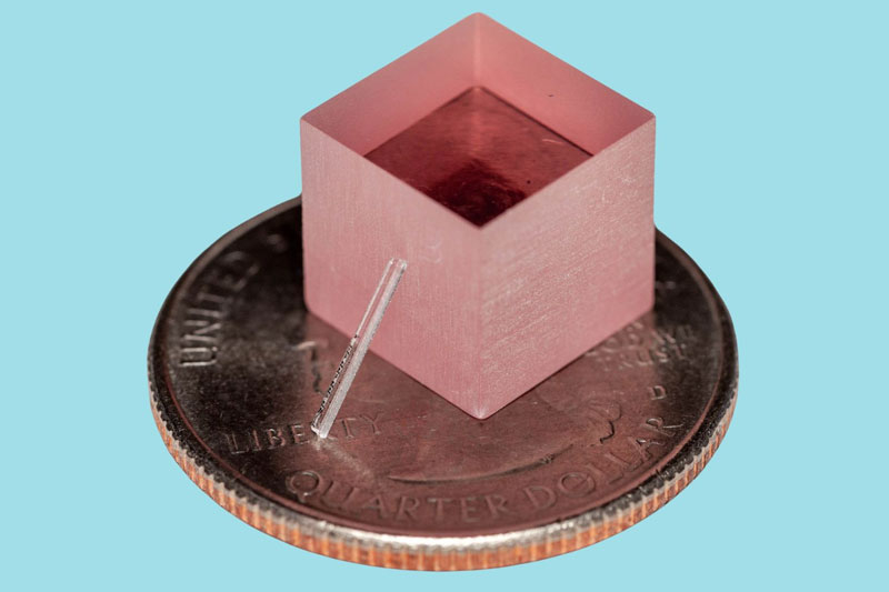  Миниатюрный лазер опирается на титаново-сапфировый кубик на фоне 25-центовой монеты. Источник изображения: Nature 
